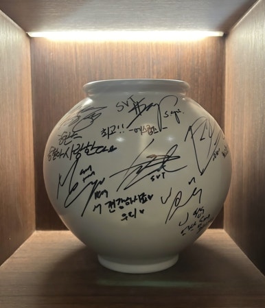 Large white Moon Jar covered in handwritten autographs from SEVENTEEN members and other Korean celebrities