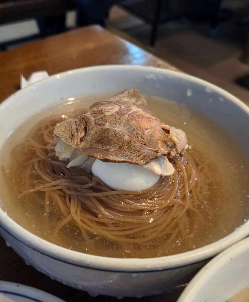 Authentic Pyongyang-style cold buckwheat noodles served in a clear beef broth.