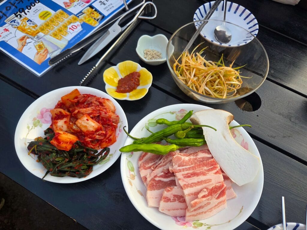 Basic BBQ setup with pork, kimchi, and vegetables on a stone grill.
Authentic Korean BBQ experience with sizzling sounds and aroma.
