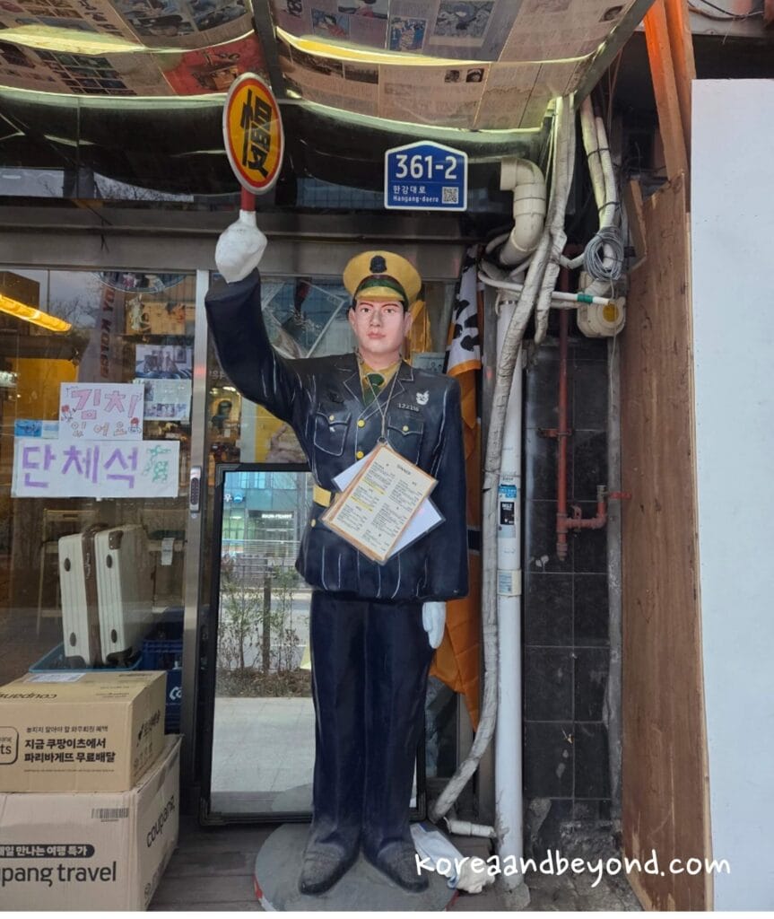 Vintage station master mannequin standing at the entrance of Tetsuro izakaya in Seoul.