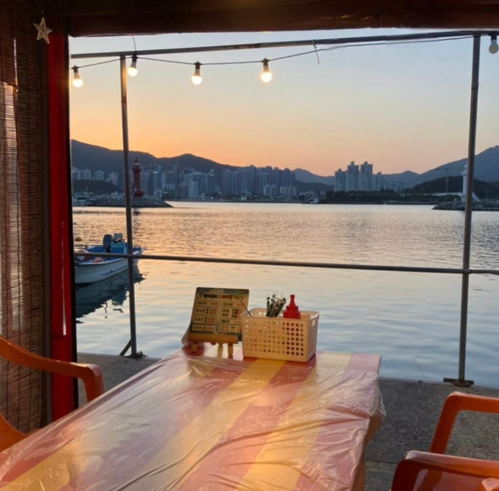 Outdoor tent seating at Hakri Breakwater in Gijang, Busan, with seafood stalls lined along the waterfront