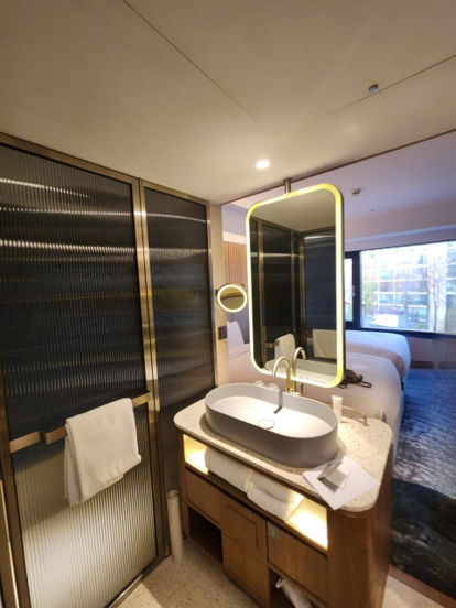 Featuring a compact, business-hotel-style vanity and bathroom located right next to the bed