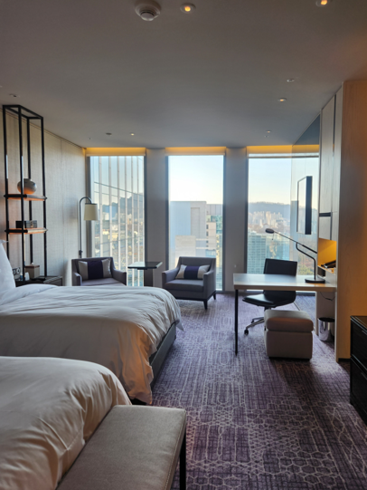 A spacious room at Four Seasons Hotel Seoul offering generous layouts with a comfortable bed area, a work table, and a tea table.
